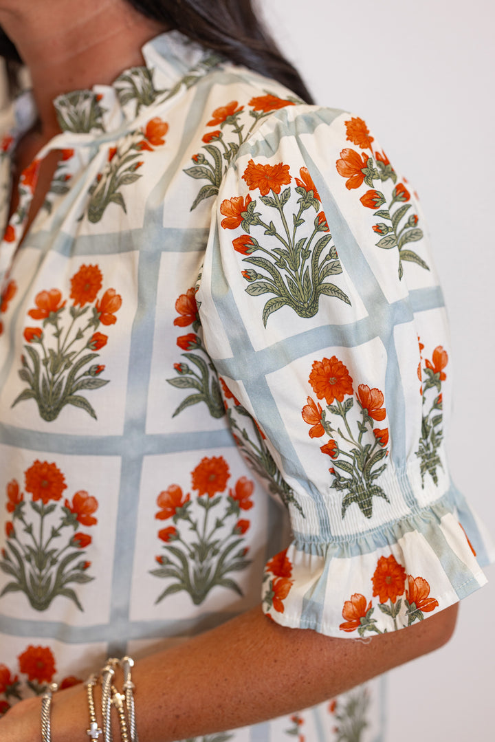 Cream top with orange floral print in light washed teal squares by Entro showing floral print detail and smocked puff sleeves