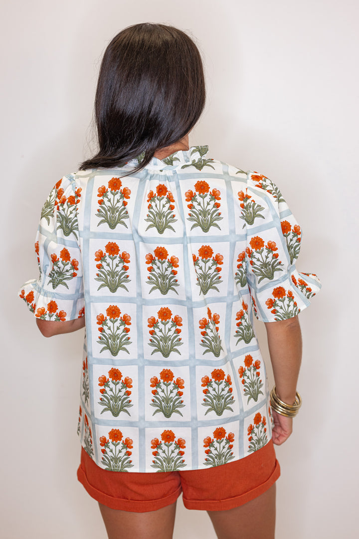 Cream top with orange floral print in light washed teal squares by Entro showing back view