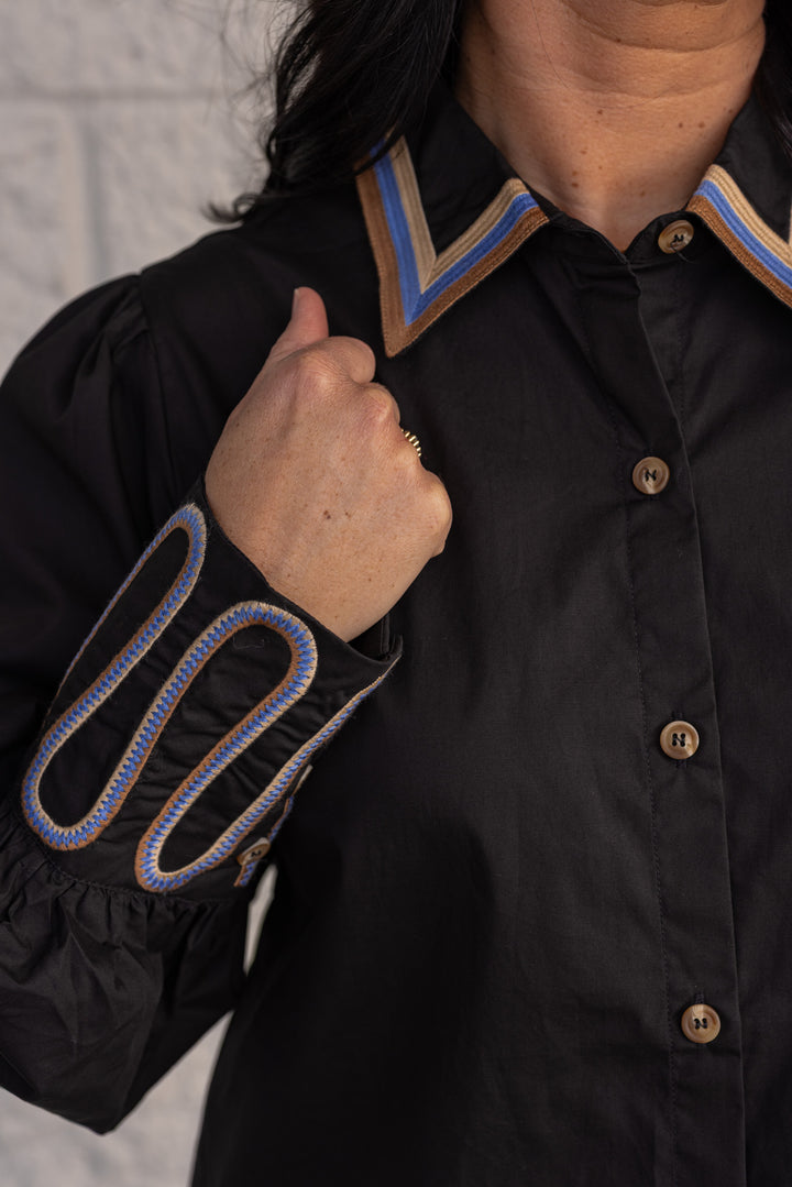 Women's black button down top by Jodifl showing brown, tan and blue embroidered details 