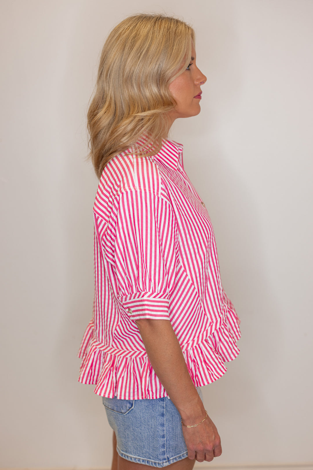 Women's pink summer striped button down top with ruffled bottom hem by Entro showing side view