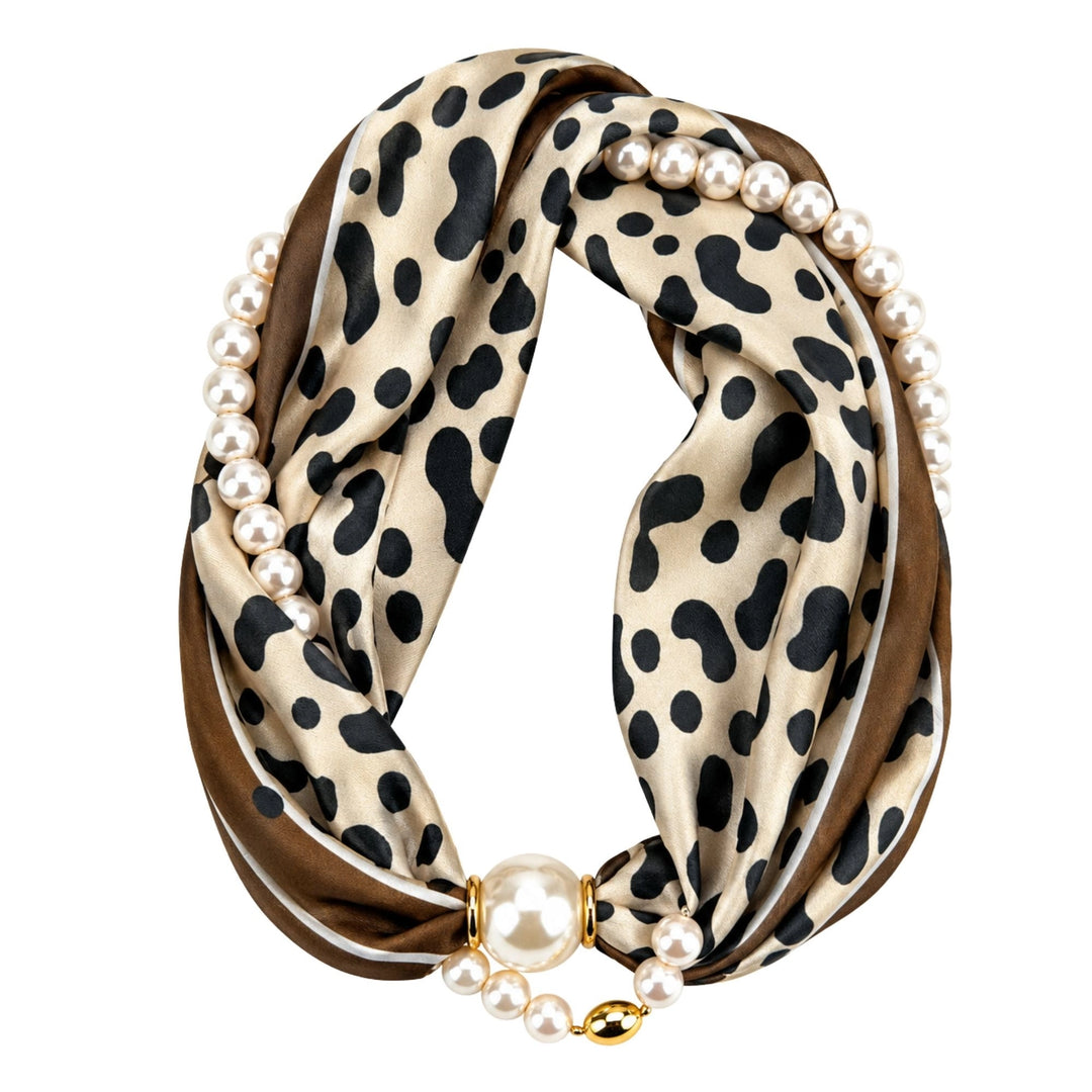 A double-loop infinity scarf featuring a beige and black leopard print outer layer, a solid brown inner layer, and decorative strands of white faux pearls with gold-tone metal accents.