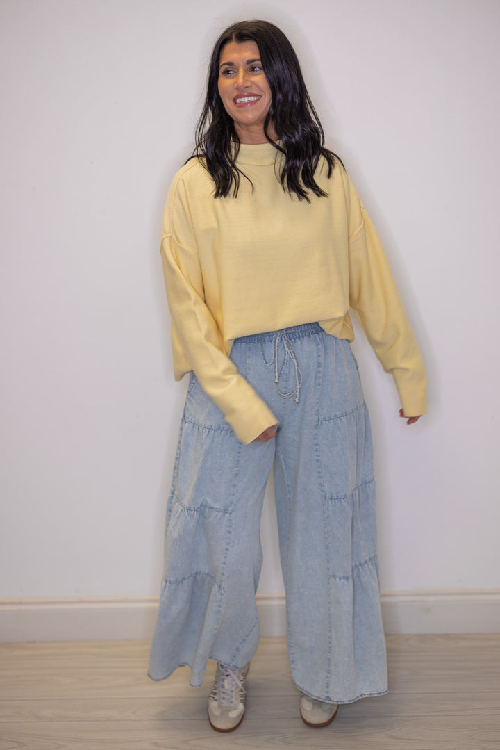 Women's light blue washed chambray denim wide leg pants, showing tiered details
