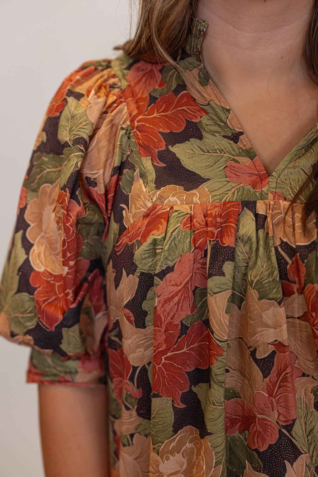 Women's brown babydoll dress with rusted burgundy, dusty peach and olive floral print by Entro showing up close view of floral print