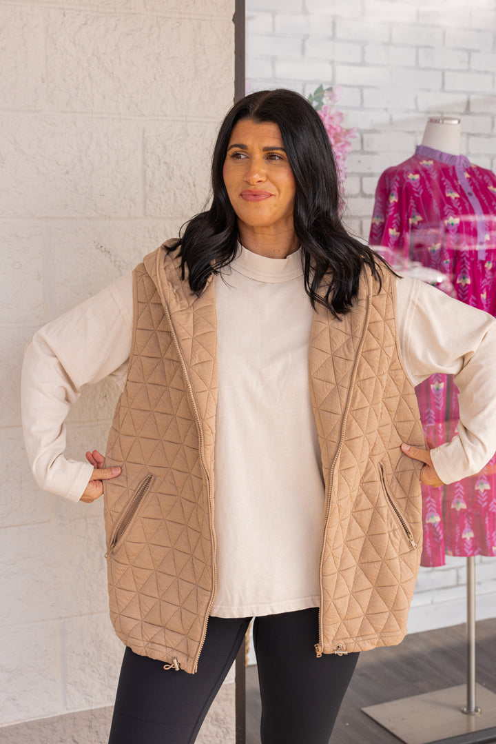 Women's taupe quilted knit puffer vest with hood and cinch hem by She + Sky showing true to size fit
